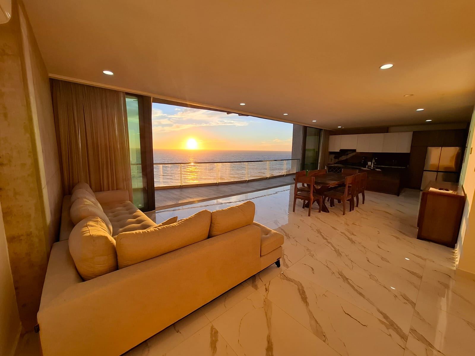 Sala y comedor con vista al mar al atardecer